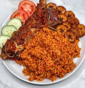 Smoky Jollof rice with fried fish and plantains_garnished_with_cucumber_and_tomatoes