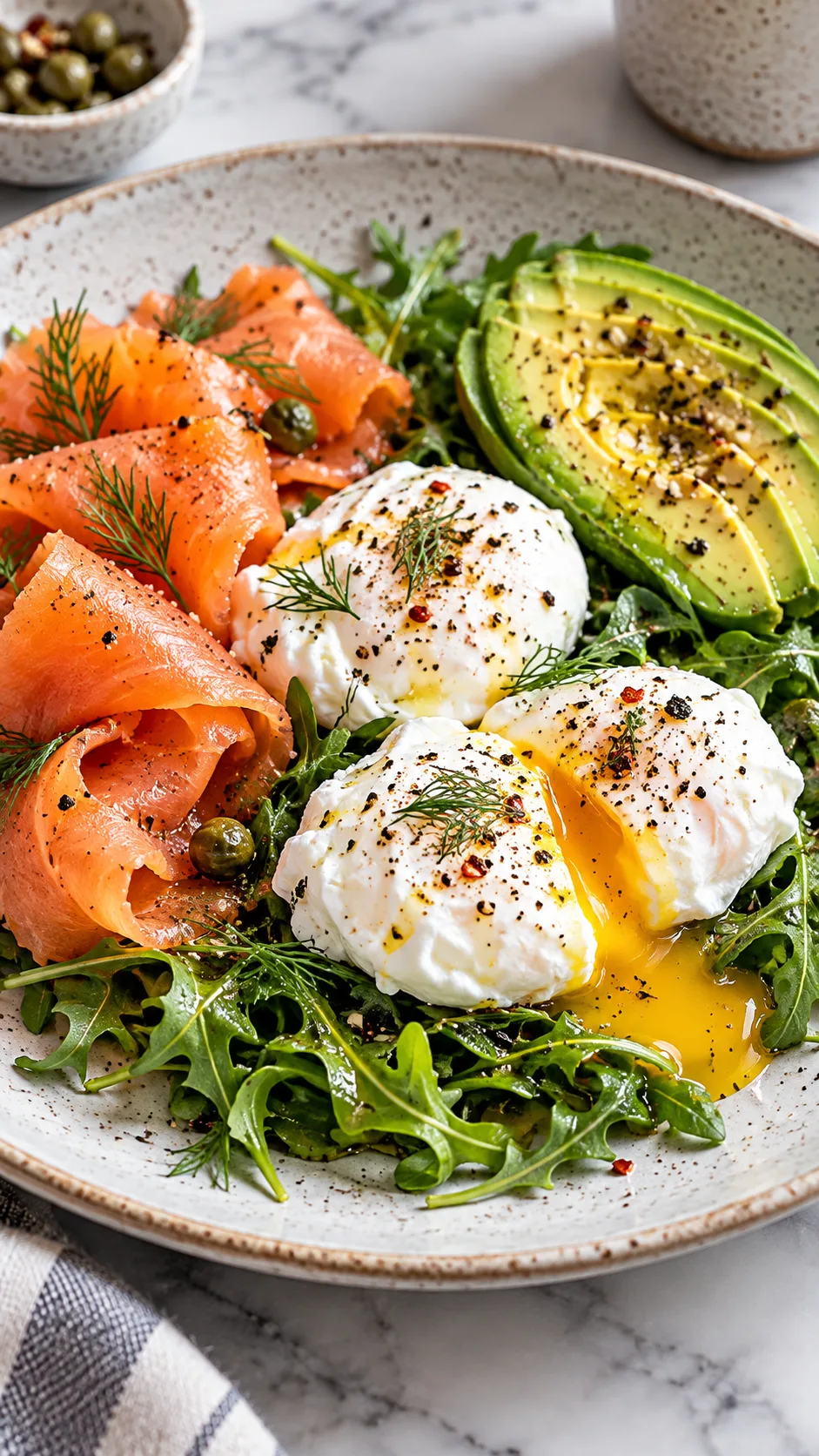Close-up of a high-protein breakfast plate featuring three poached eggs, smoked salmon, half a sliced avocado, and a bed of dressed arugula on a modern ceramic plate.